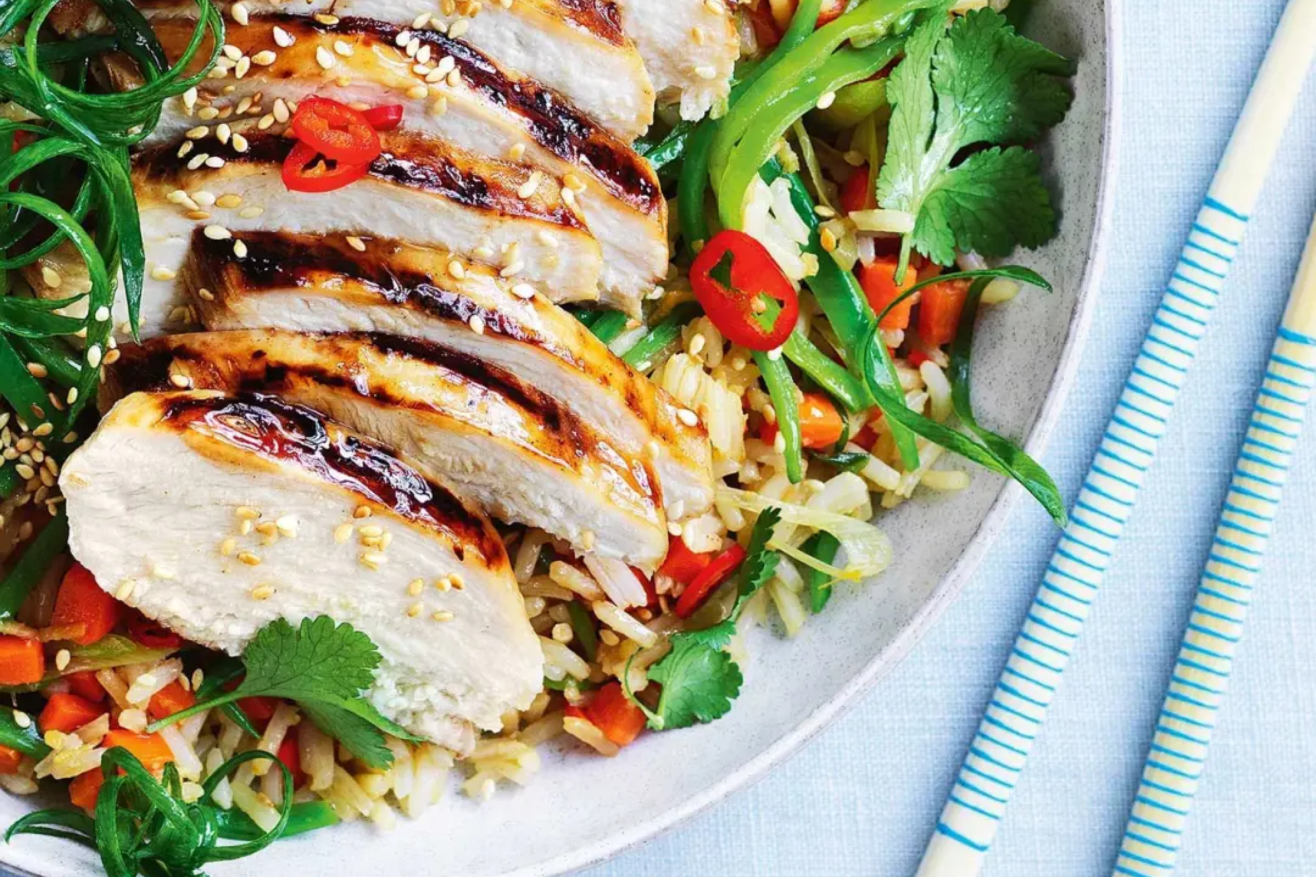 Grillezett csirkés és zöldséges rizs tál avokádóval és friss korianderrel tálalva